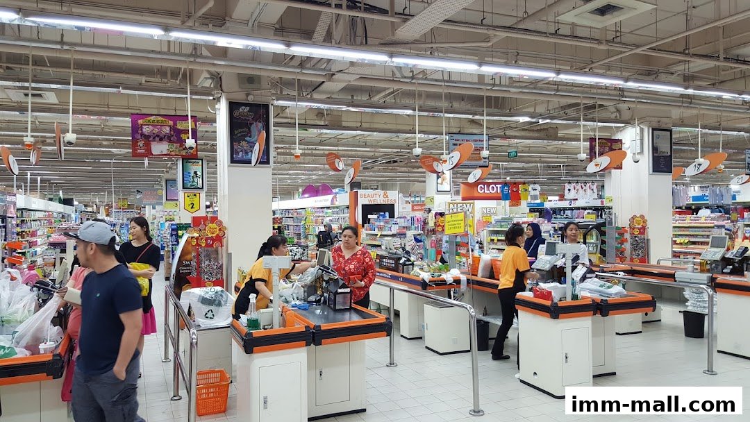 Customers and staff at checkout counters in a brightly lit supermarket.