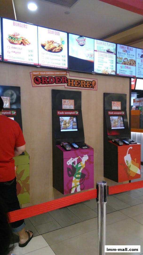 A Popeyes restaurant interior with digital menu boards and self-order kiosks.