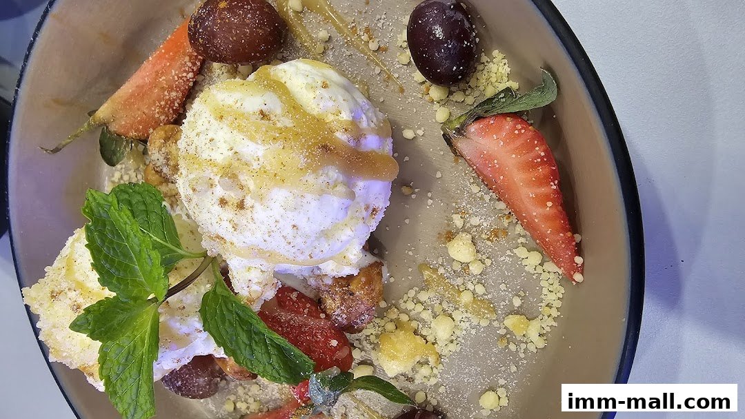 A close-up of a dessert with ice cream, strawberries, grapes, and mint.