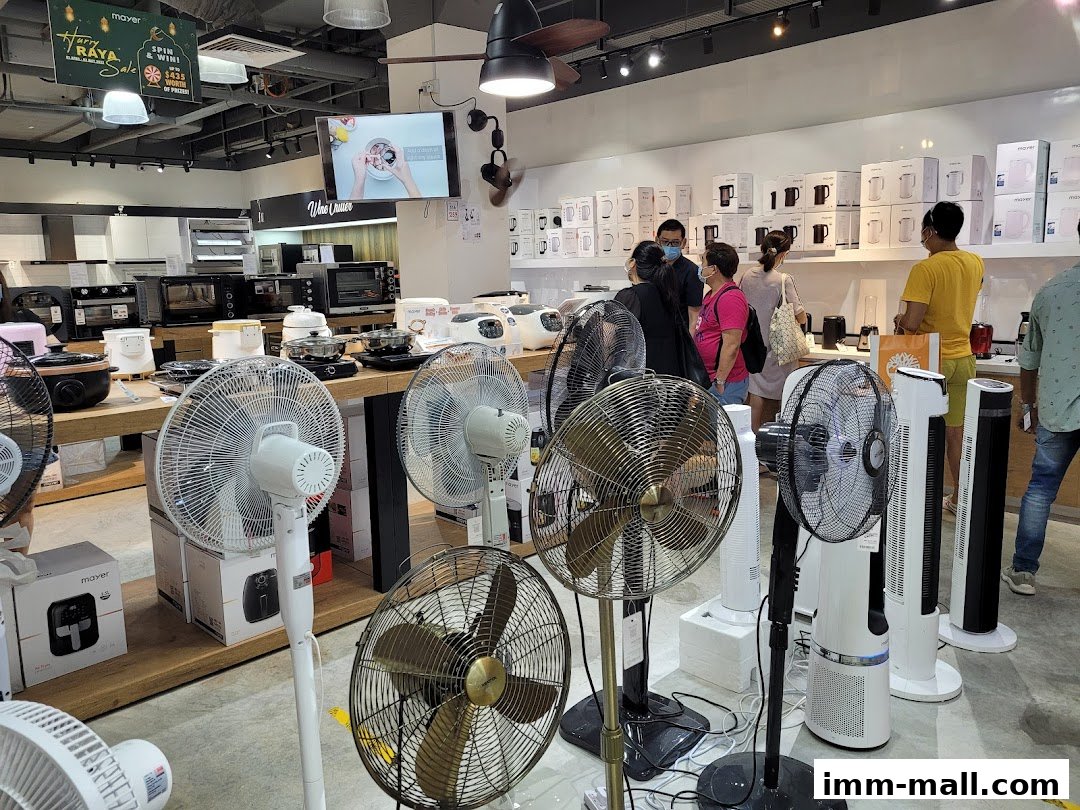 Interior of a retail store showcasing various fans and kitchen appliances with customers browsing.
