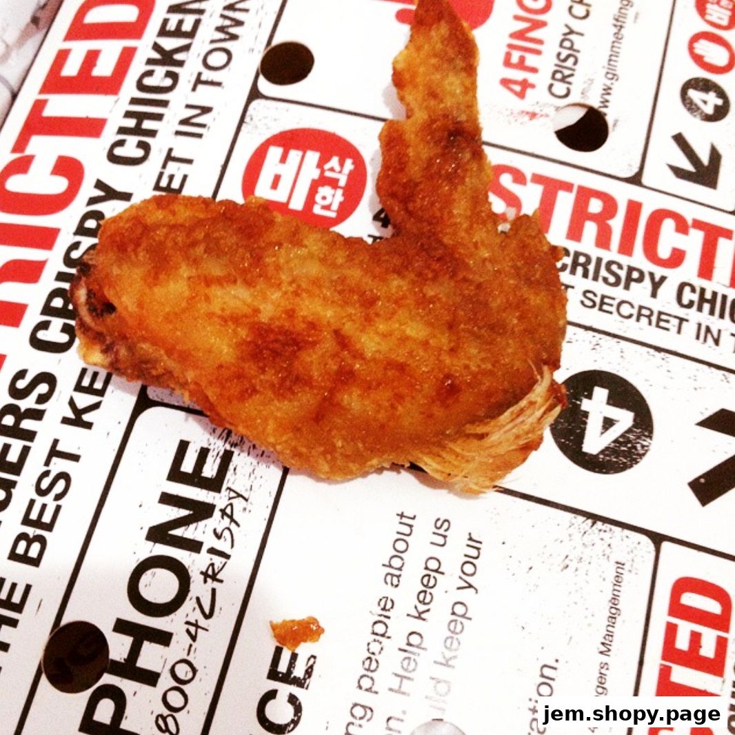 A close-up shot of a crispy chicken wing on a branded paper.