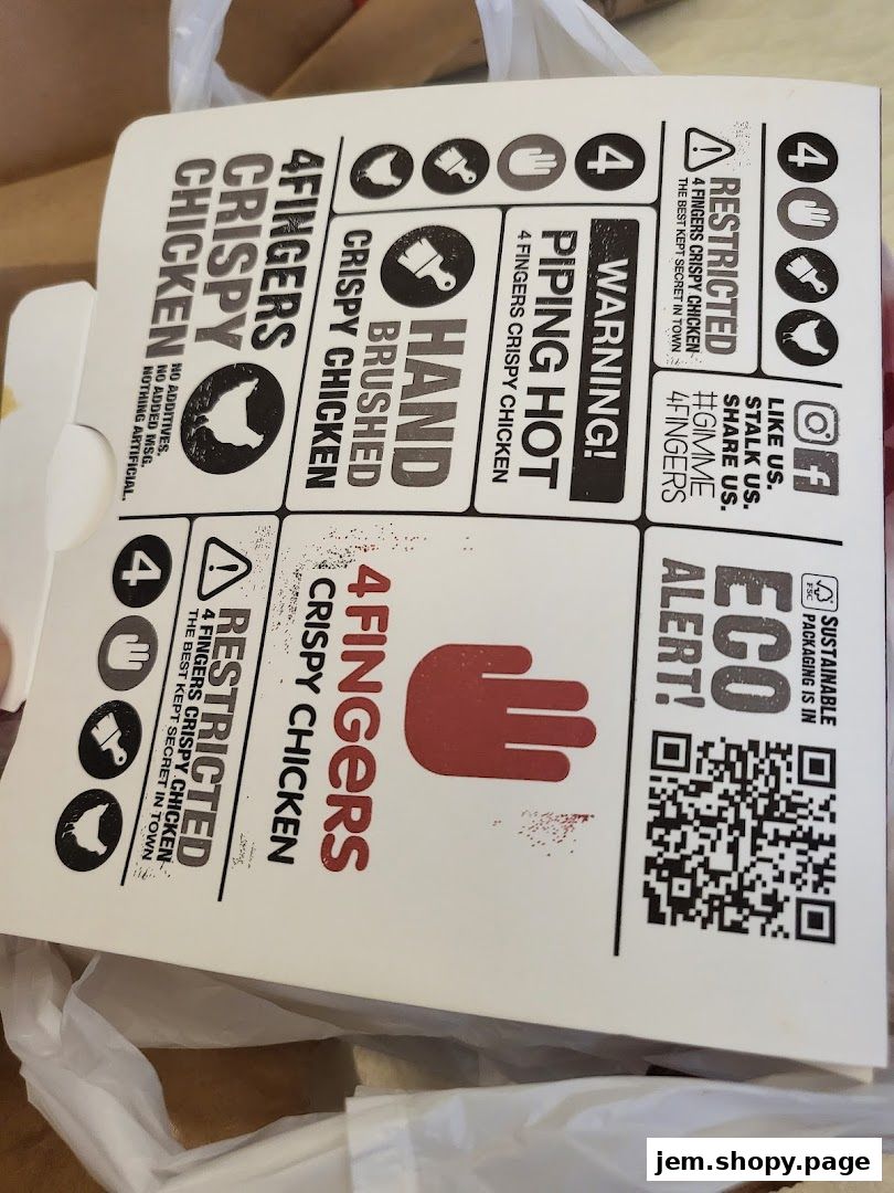 A close-up of a 4 Fingers Crispy Chicken box with branding and warnings.