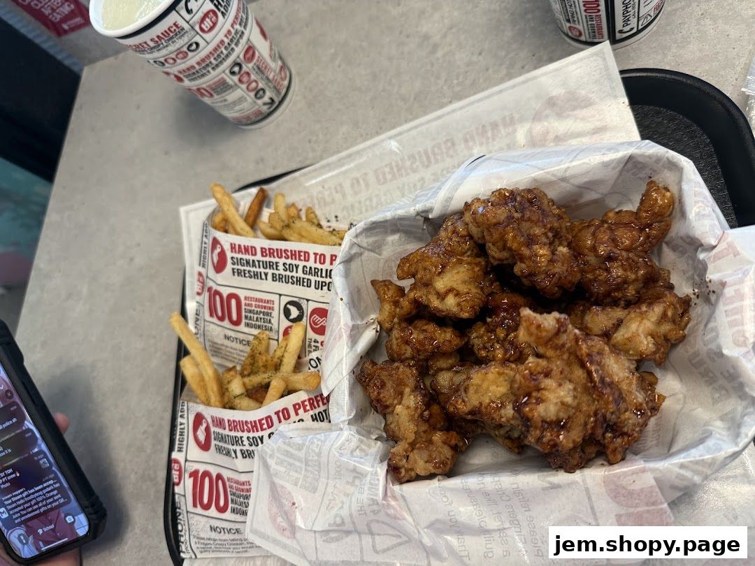 A basket of crispy chicken pieces and two servings of fries with a drink.