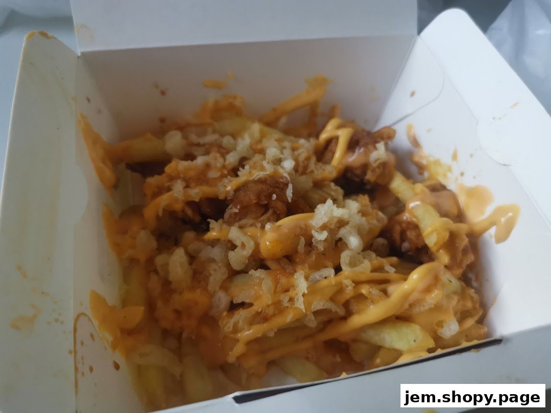 A box of crispy chicken fries topped with cheese sauce and crispy onions.