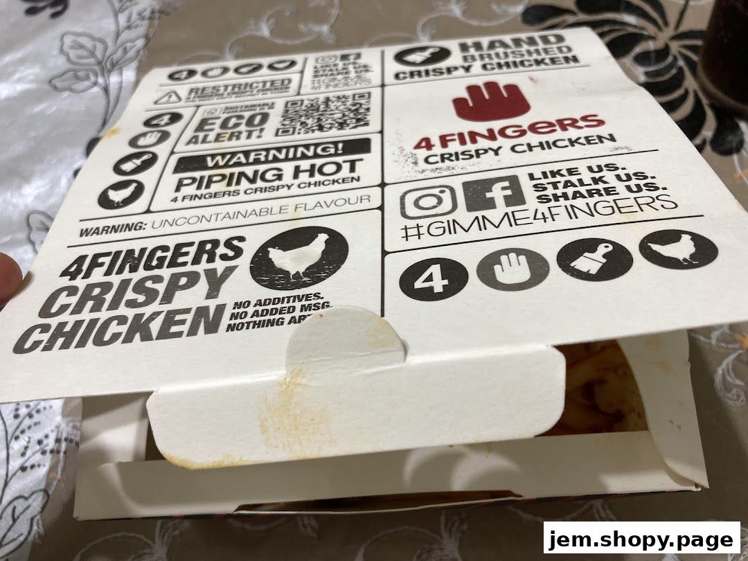 A close-up of a 4 Fingers Crispy Chicken box with branding and warnings.