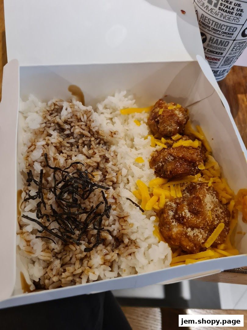 A box of crispy chicken with rice, shredded cheese, and seaweed.