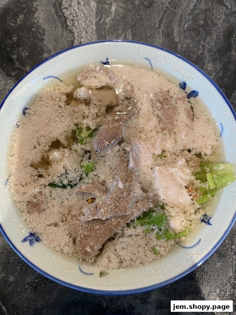 A close-up shot of a bowl of noodle soup with meat and vegetables.