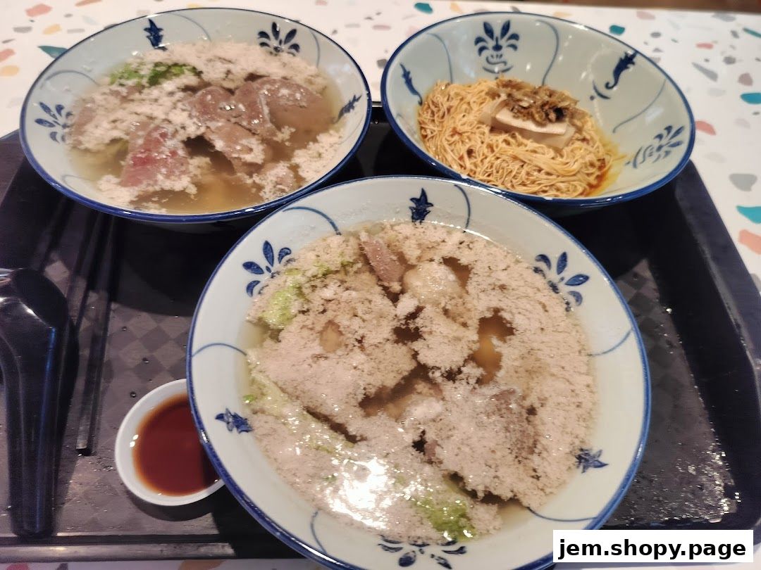 Three bowls of noodles and a small dish of sauce on a tray.