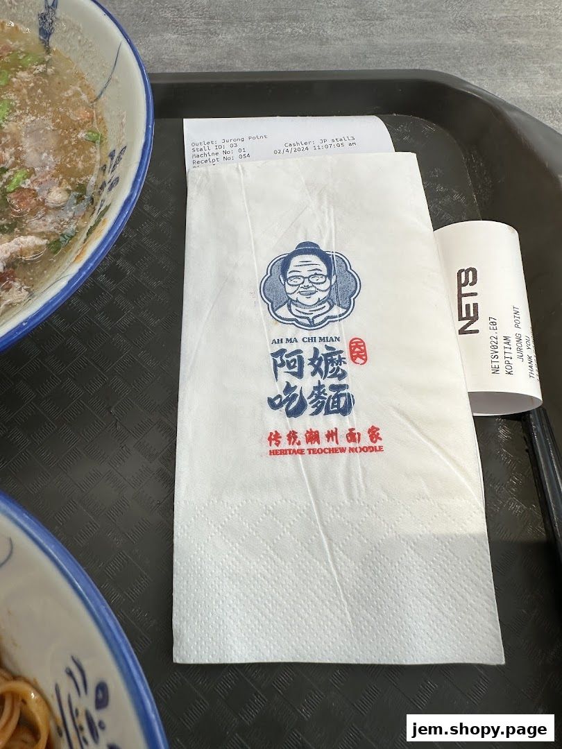 A close-up of a napkin with the logo of Ah Ma Chi Mian and a receipt.