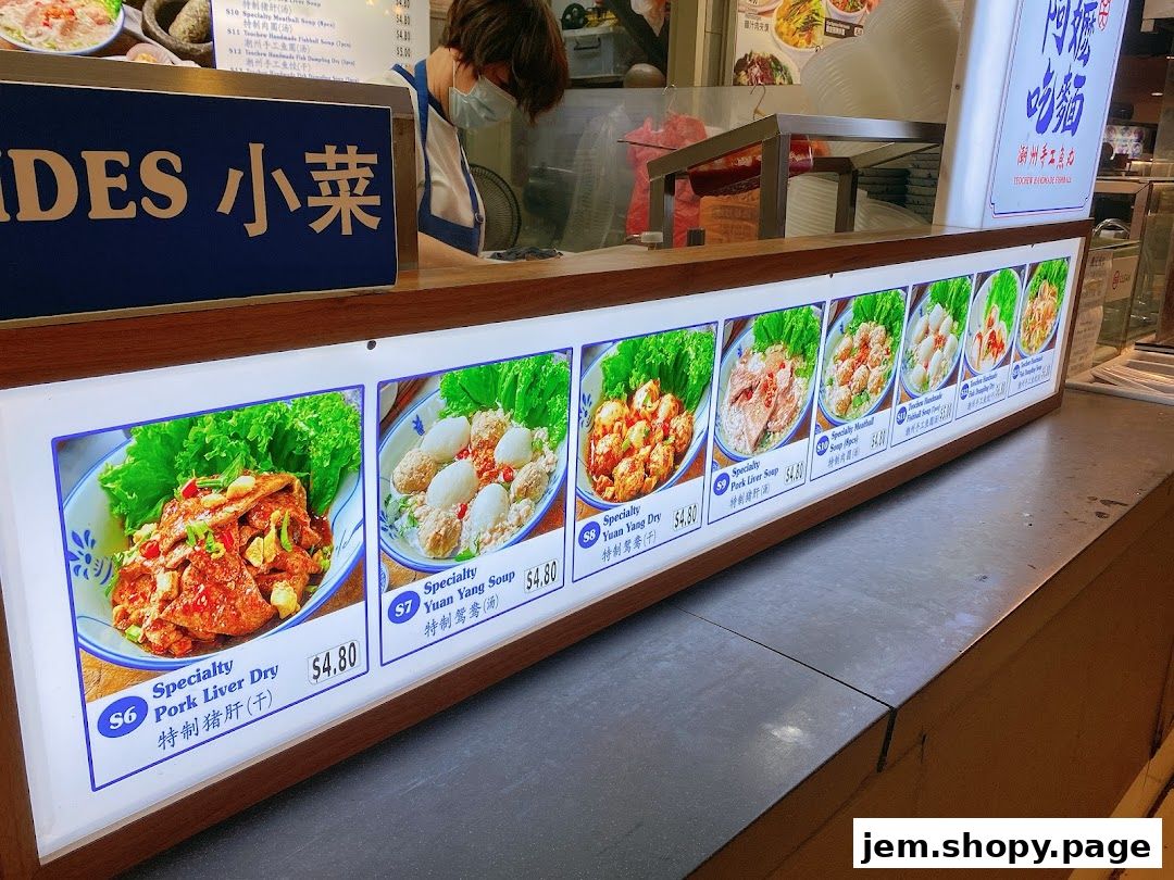 A brightly lit menu display showcasing various noodle dishes and side dishes from Ah Ma Chi Mian.