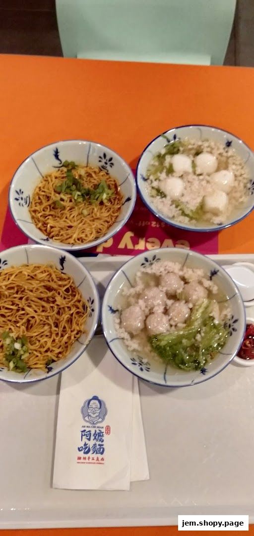 Bowls of noodles and soup with meatballs are served on a tray.