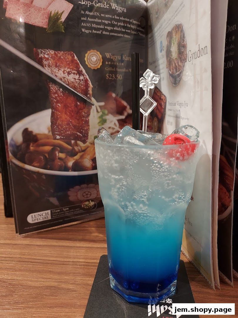 A blue cocktail sits on a table next to a menu featuring wagyu beef dishes.