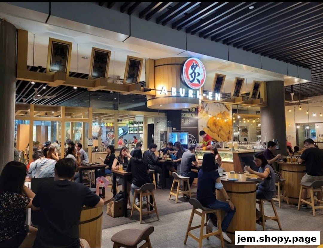 A busy Aburi-EN Jem restaurant with customers dining at tables and a visible storefront.