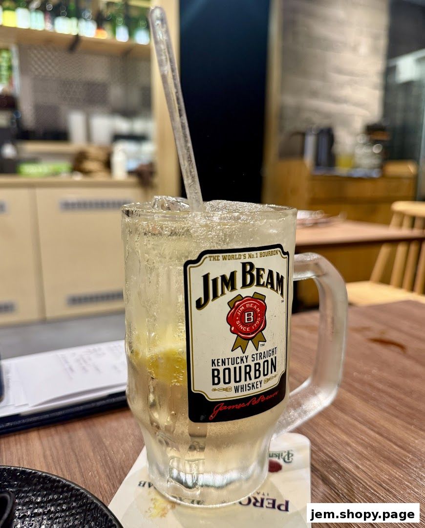 A refreshing Jim Beam bourbon highball with ice and lemon in a branded mug.