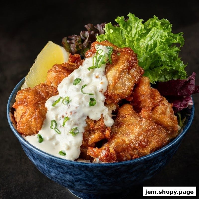 A close-up of a delicious bowl of Japanese fried chicken with sauce and garnish.