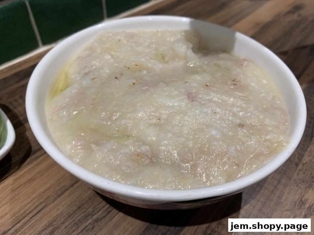 A close-up shot of a bowl of traditional porridge with visible meat pieces.