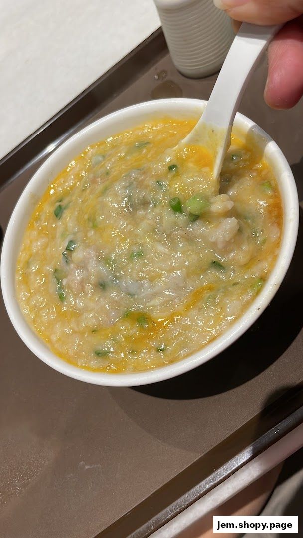 A close-up shot of a bowl of savory porridge with chopped green onions.