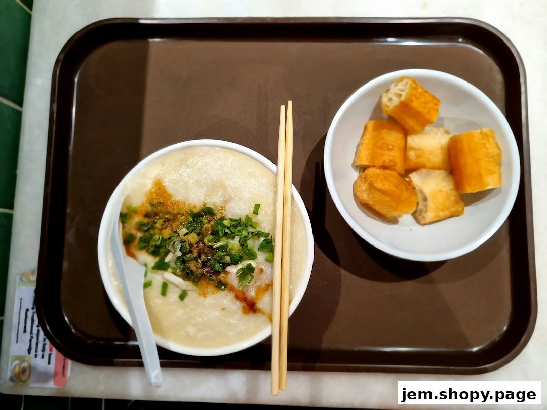 A bowl of traditional porridge with toppings and a side of fried dough sticks on a tray.