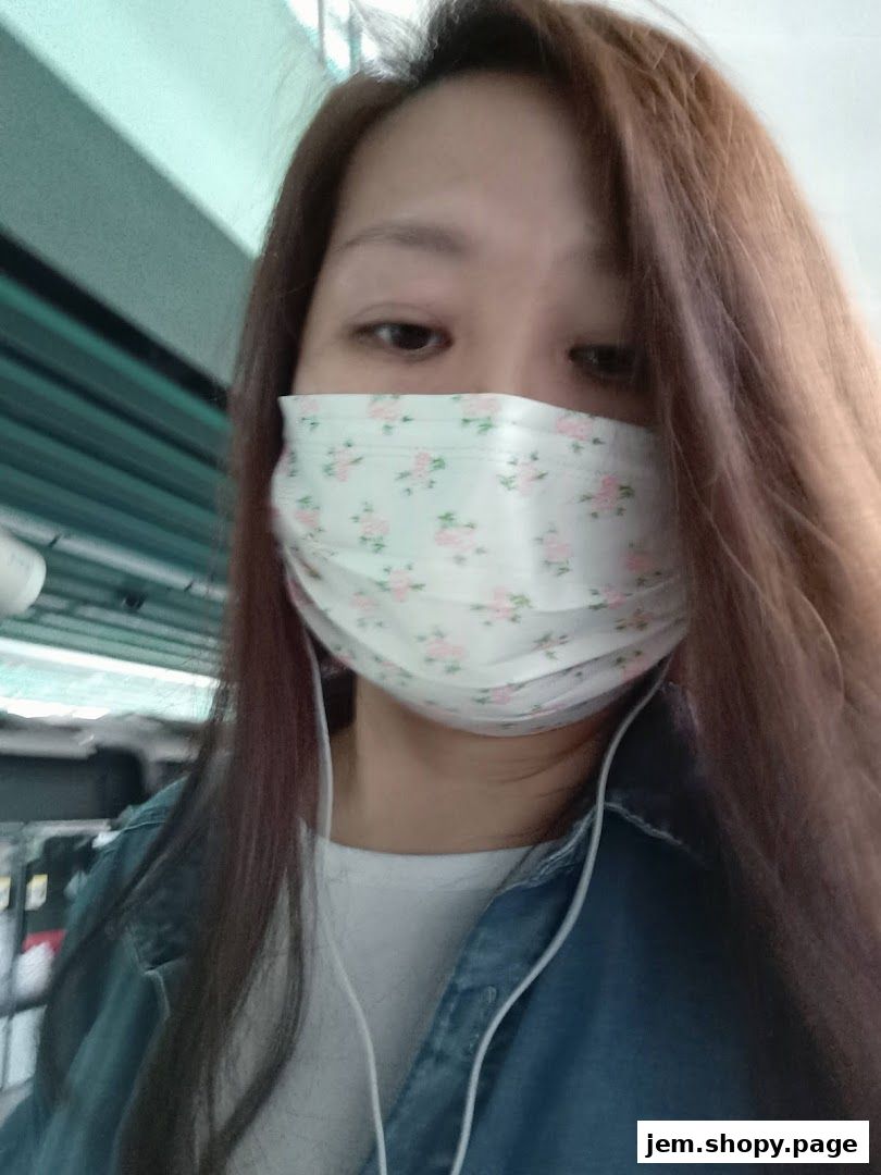A woman wearing a floral face mask and headphones, with long brown hair.
