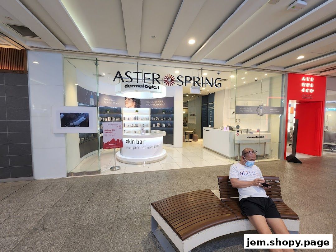 The exterior of AsterSpring, a skin care shop, with products displayed inside and a person sitting on a bench.
