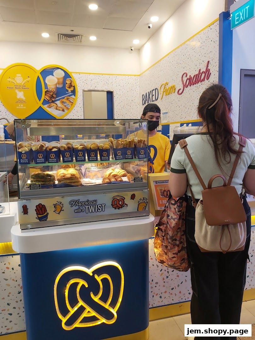 A customer orders pretzels at an Auntie Anne's counter with freshly baked goods on display.