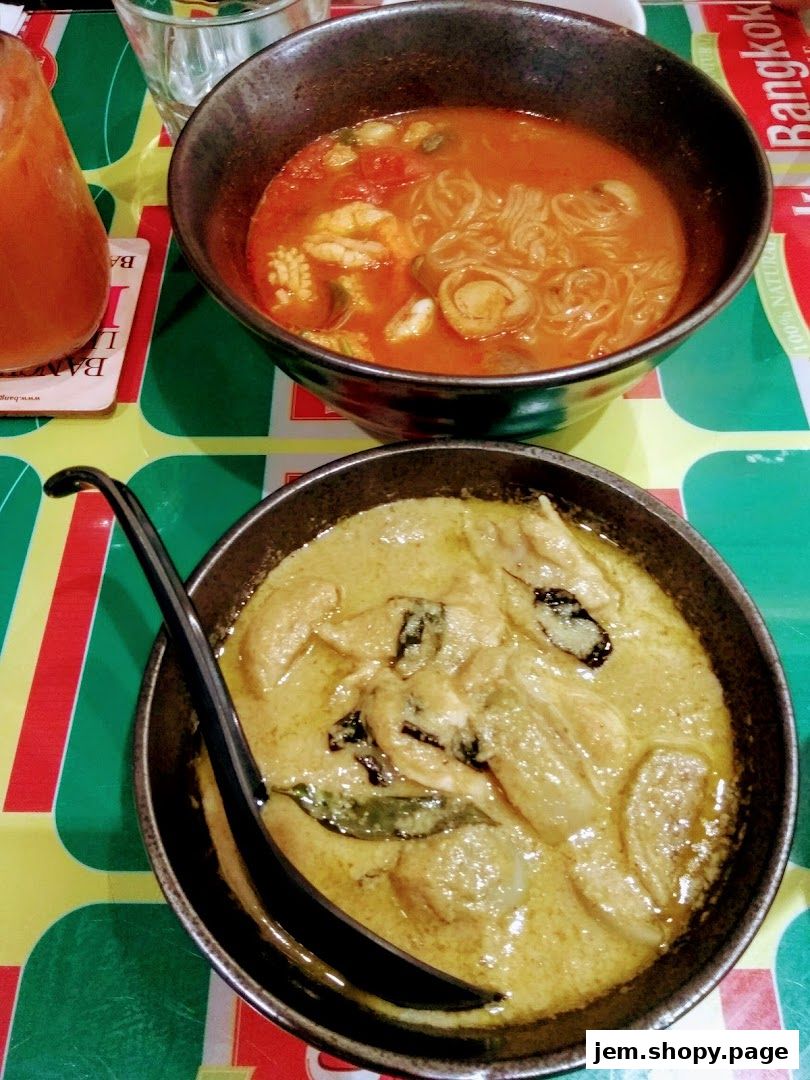 Two bowls of Thai food, one with green curry and chicken, the other with soup and noodles.