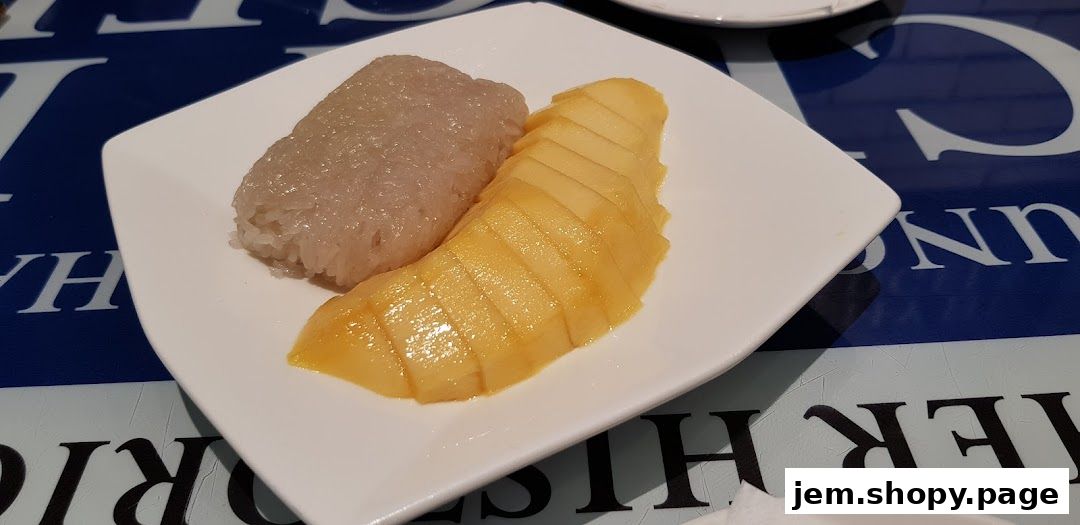 A white plate with mango slices and sticky rice on a blue and white patterned surface.