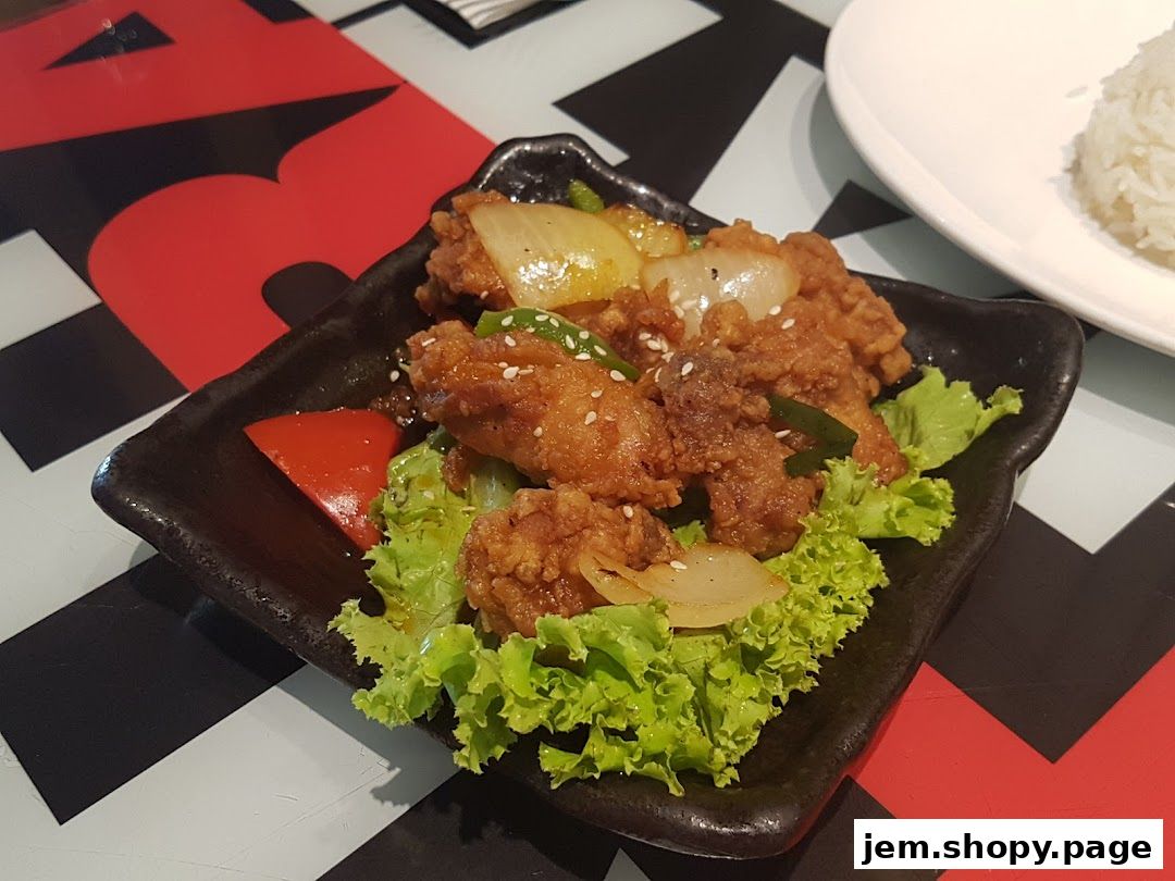 A plate of crispy fried chicken with onions and bell peppers, served with rice.