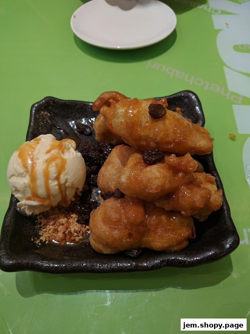A plate of fried bananas with ice cream and nuts on a green table.