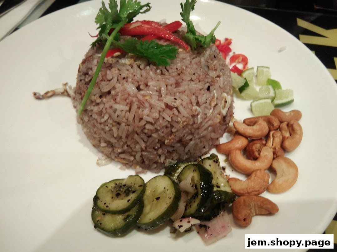 A plate of Thai fried rice with cashews, lime, chili, and cucumber.