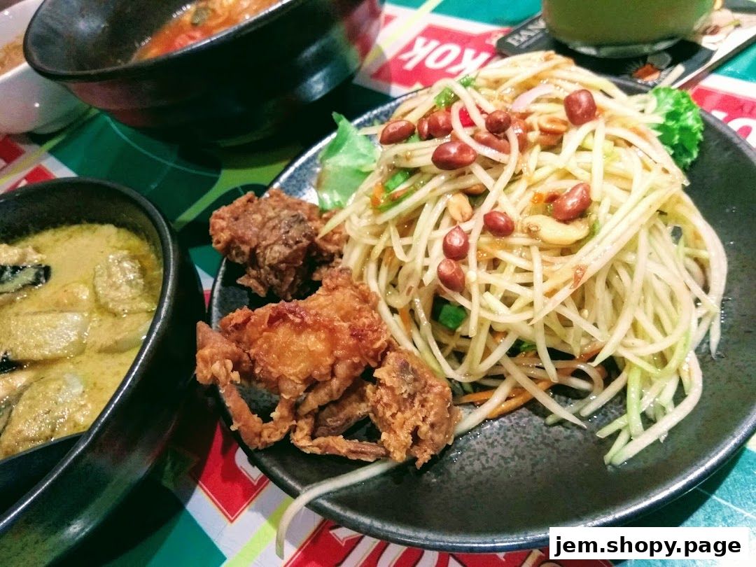 A close-up of Thai dishes including green curry, fried soft shell crab, and papaya salad.