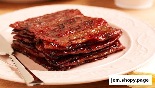 A stack of glistening, sweet bak kwa slices on a pink plate with a serving utensil.