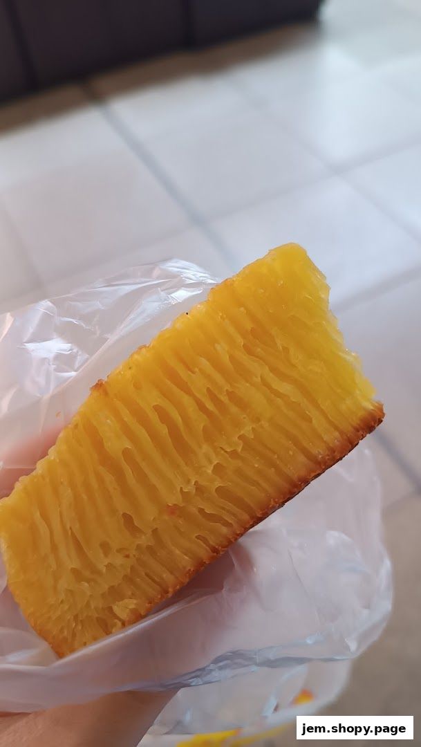 A slice of golden honeycomb cake wrapped in plastic.