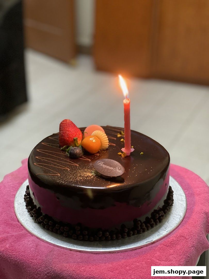 A decadent chocolate cake with fresh fruit and a lit candle from Bengawan Solo.