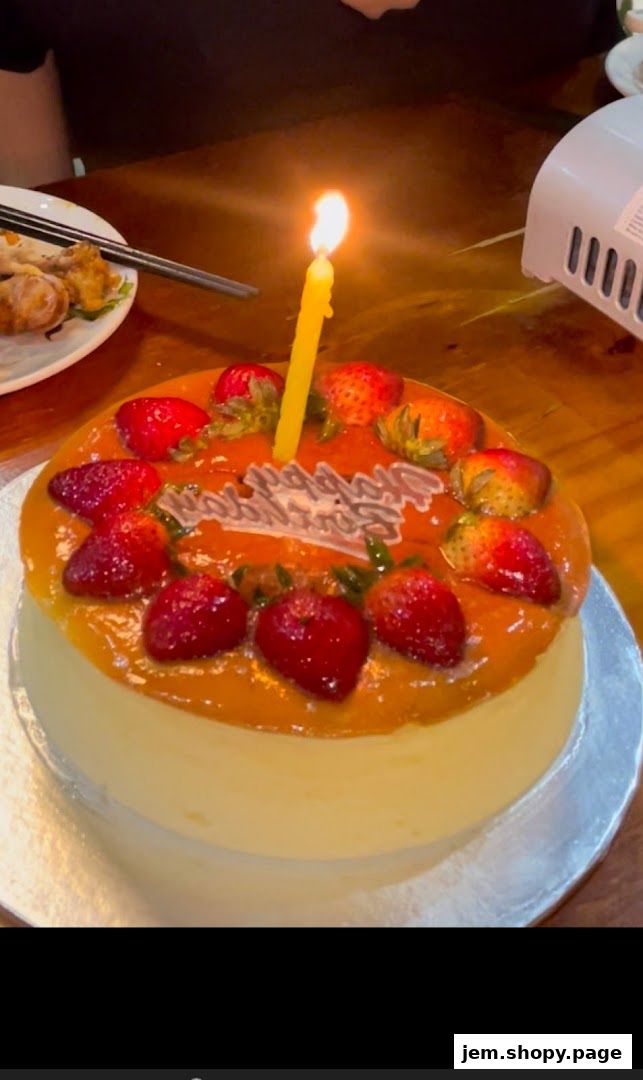 A delicious cake decorated with strawberries and a lit birthday candle.