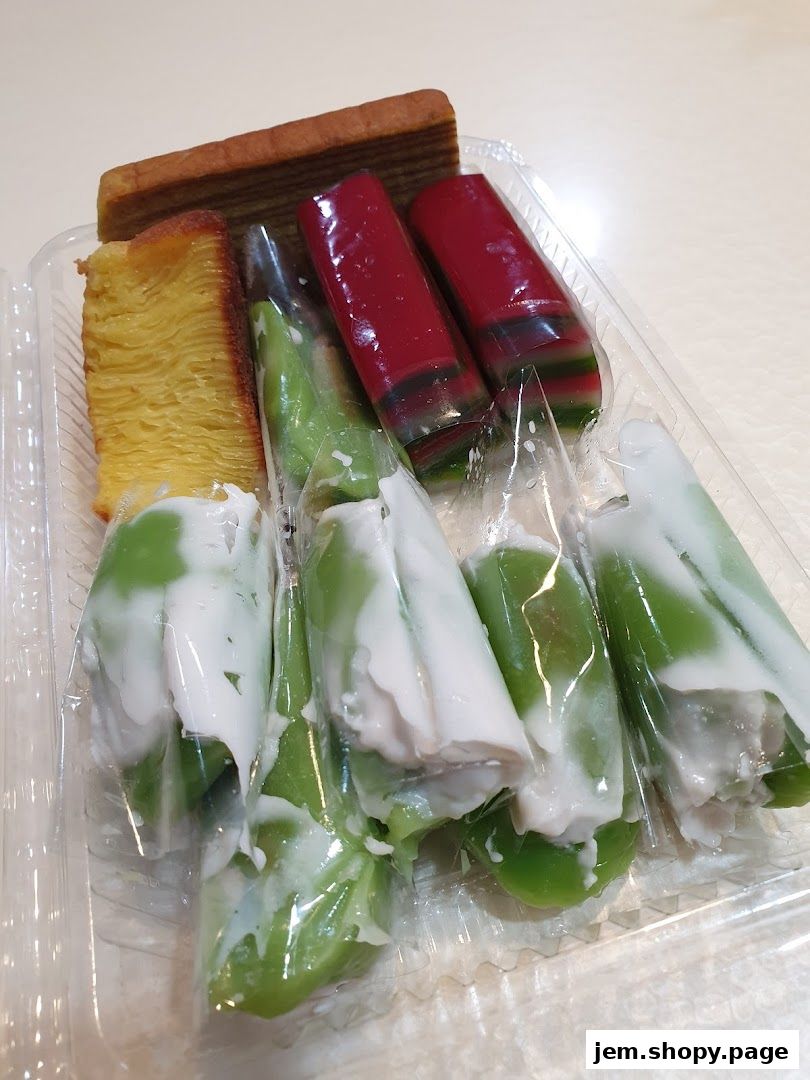 A clear plastic container filled with assorted Indonesian kue (cakes) and desserts.