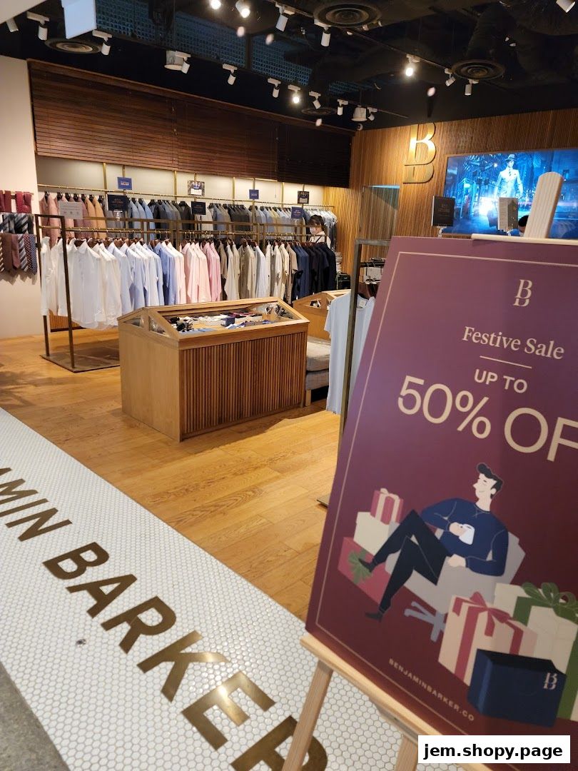 Interior of Benjamin Barker shop with shirts on display and a festive sale sign.