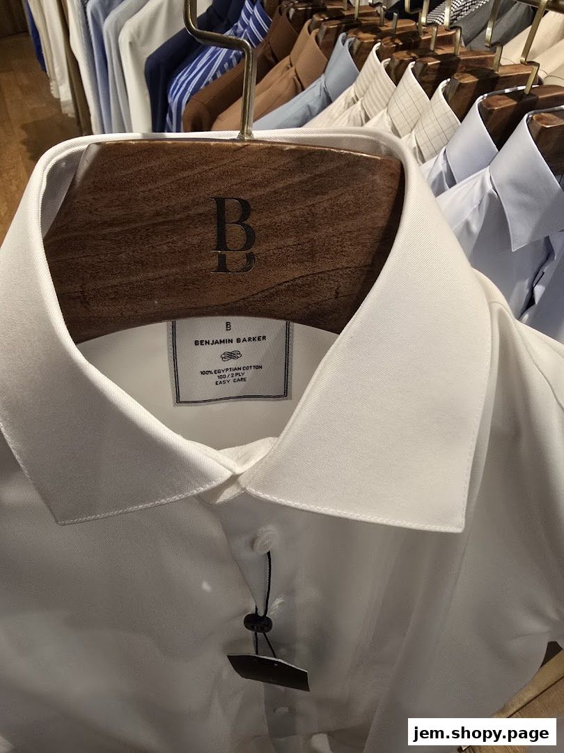 Close-up of a white Benjamin Barker shirt on a wooden hanger with other shirts in the background.