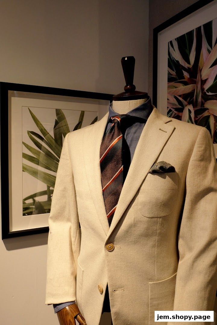 Mannequin dressed in a light beige suit jacket, blue shirt, and striped tie.