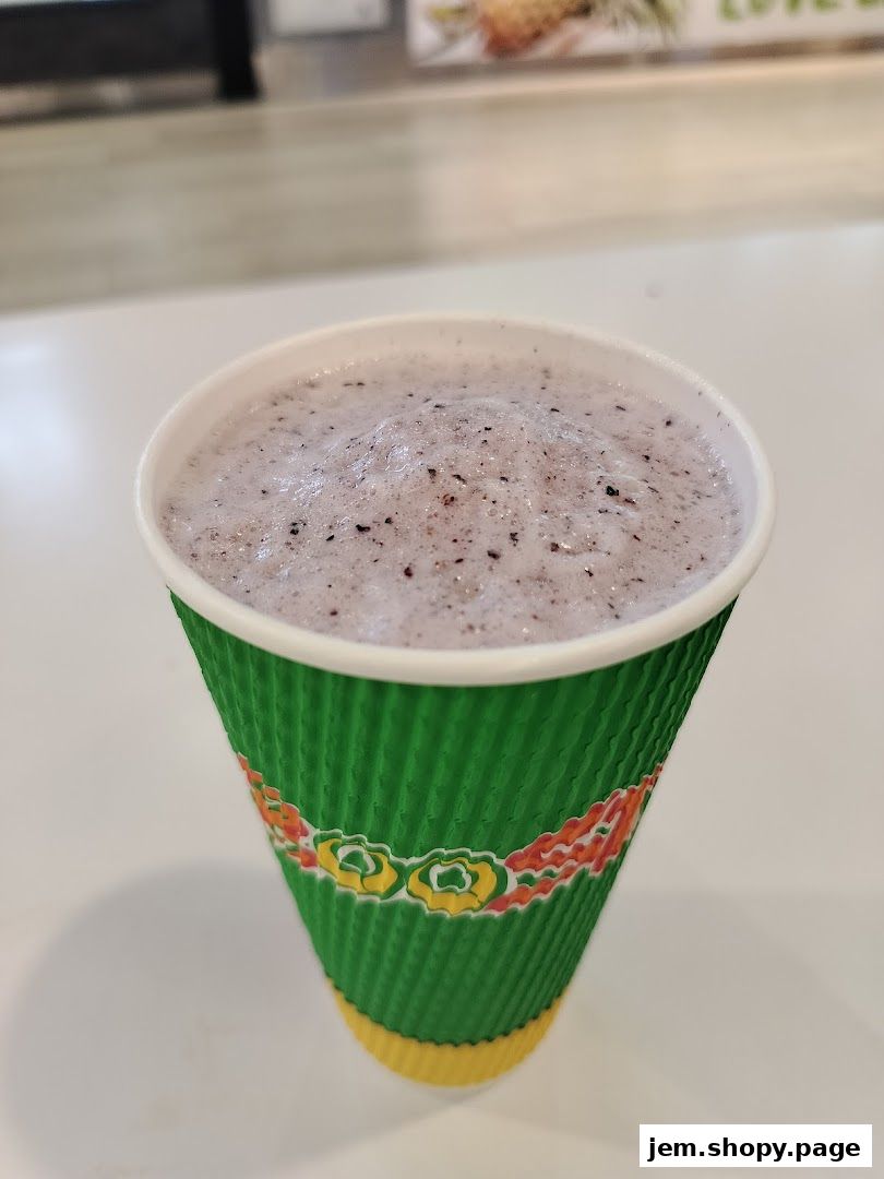 A close-up of a purple smoothie in a green and yellow branded cup.