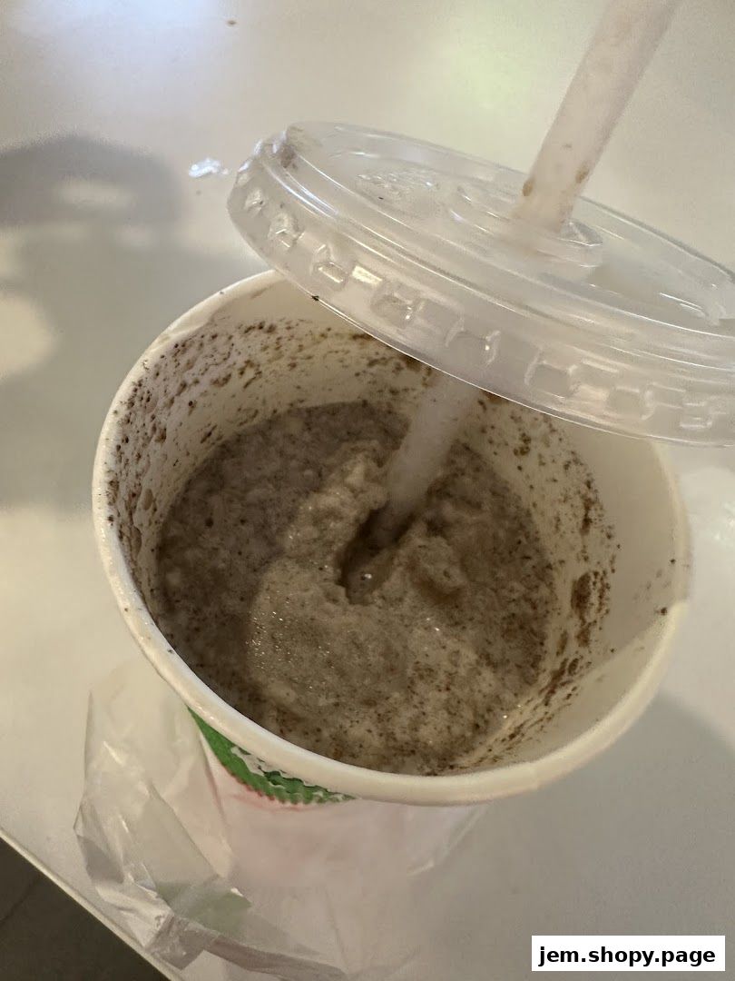 A close-up of a cookies and cream smoothie in a cup with a straw and lid.