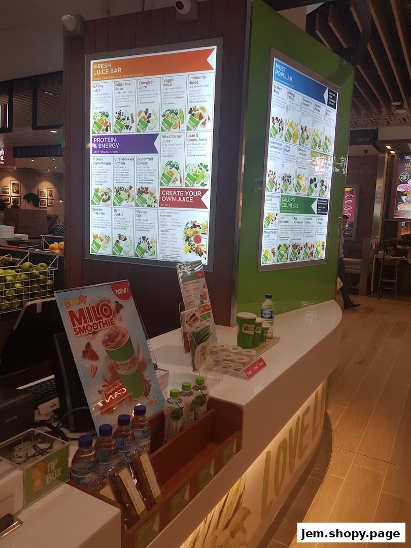 A juice bar counter displaying various fresh juice and smoothie options on illuminated menus.