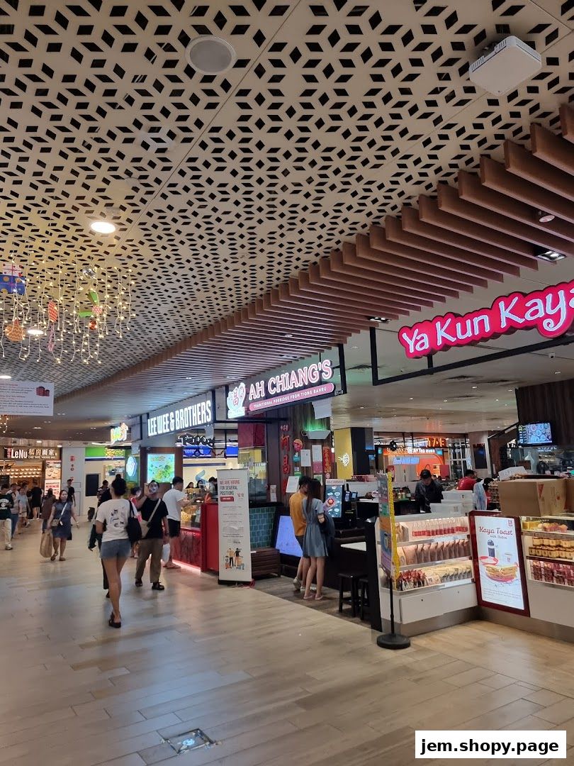A bustling mall walkway with various food stalls and shoppers.