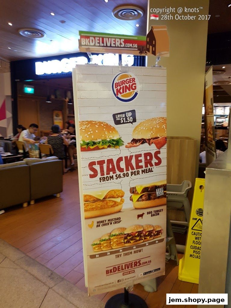 A Burger King promotional stand displays stacker burgers and delivery information.