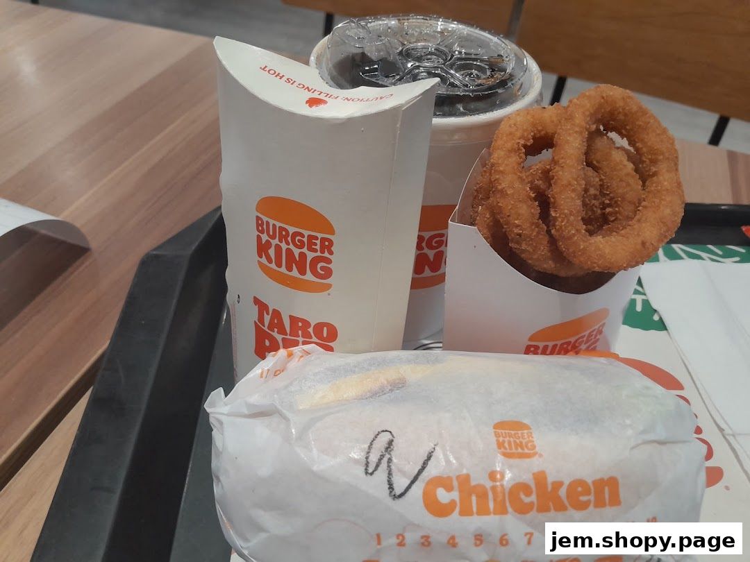 A Burger King meal featuring a chicken burger, onion rings, and a drink.