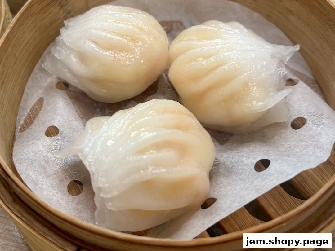 A close-up shot of three steamed har gow dumplings in a bamboo steamer.