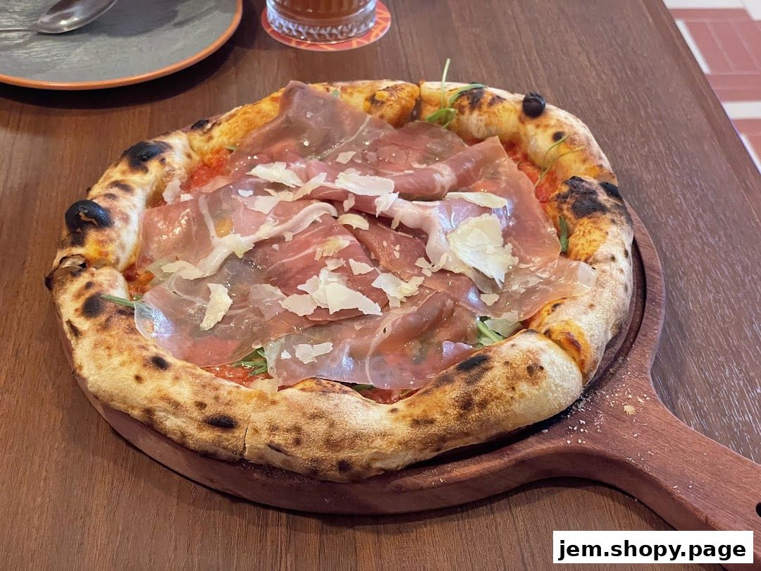 A delicious pizza with prosciutto and shaved parmesan cheese on a wooden board.