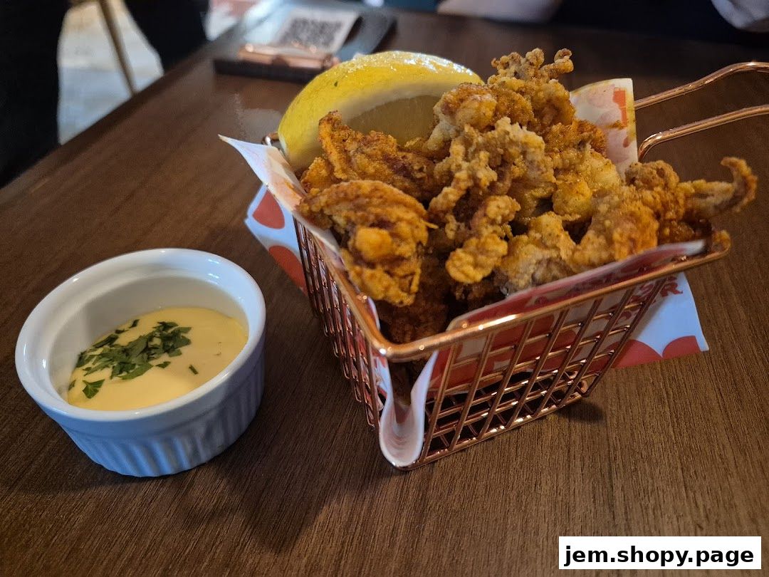 Crispy fried calamari served in a rose gold basket with a lemon wedge and dipping sauce.