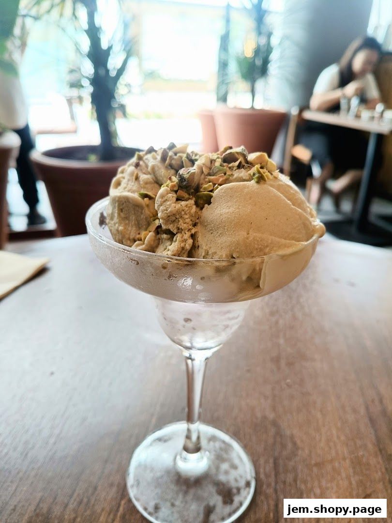 A close-up of pistachio ice cream served in a glass goblet on a wooden table.