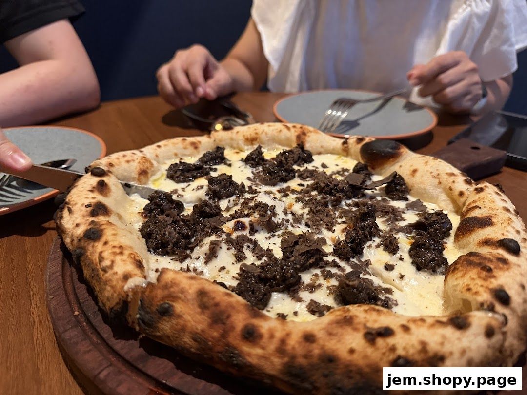 A close-up of a truffle pizza being cut at a table in a restaurant.